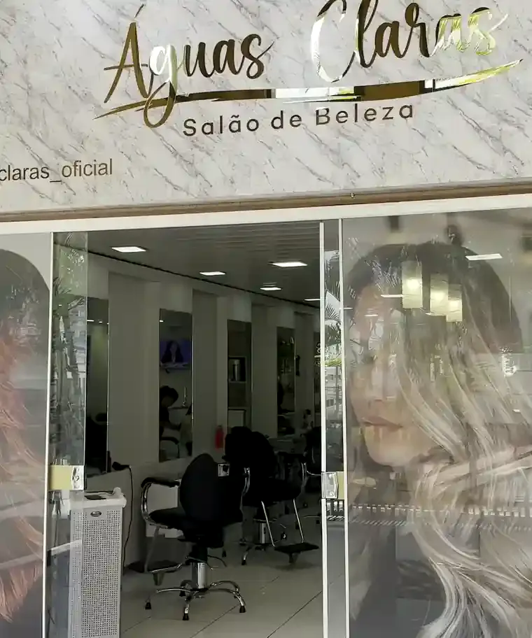 Letreiro do salão em mármore com o nome Águas Claras em dourado, sobre a porta de vidro
